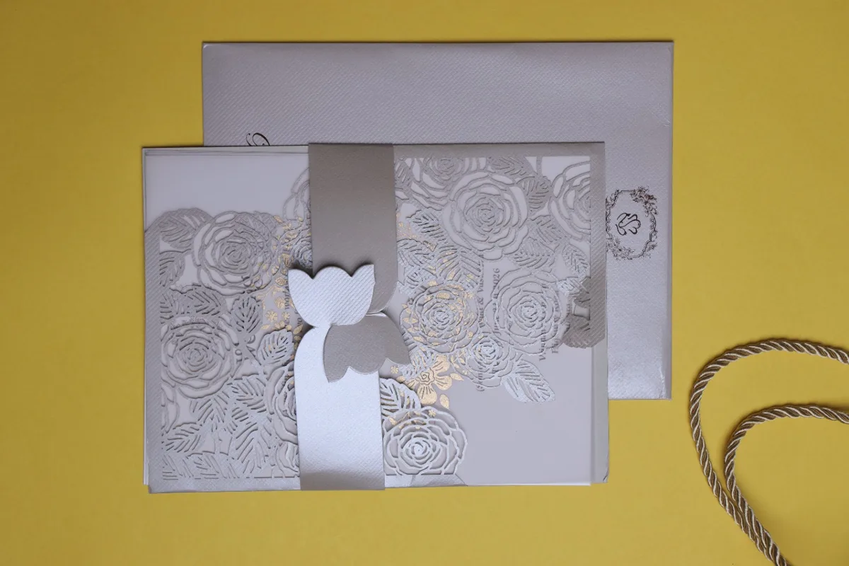 Silver laser-cut floral wedding invitation with matching envelope