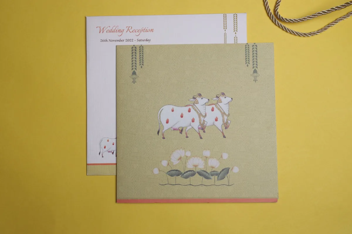 Sage green wedding reception card with Pichwai-style cow and lotus artwork
